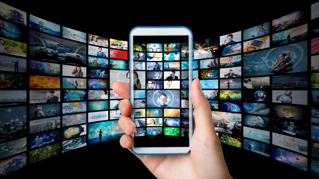 無数の映像パネルに囲まれて、スマートフォンを掲げる手