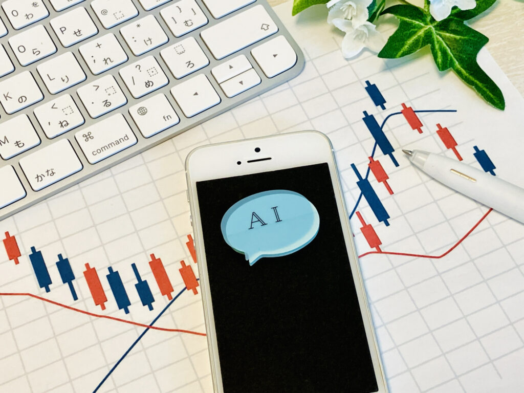 ローソク足の株価チャートの上に置かれた、「AI」と表示されたスマートフォン